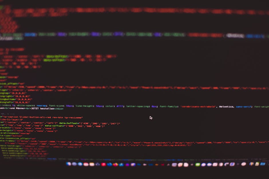 Close-up image of a computer screen displaying a black background with colorful lines of HTML and CSS code in red, green, blue, purple, and yellow. The code appears to be part of a website's front-end